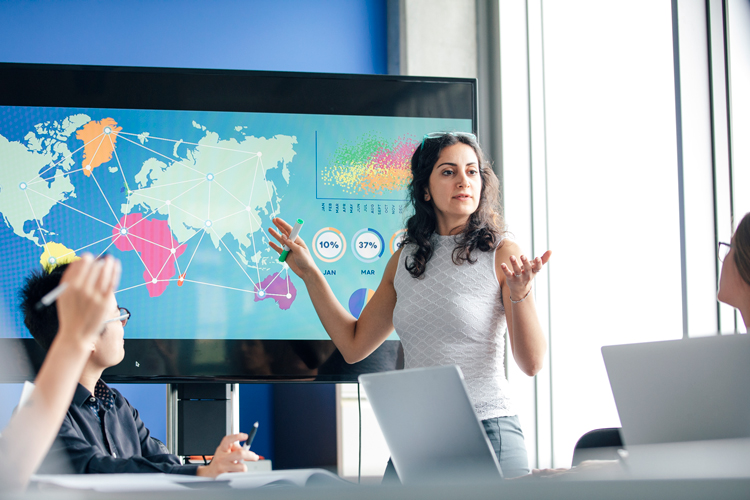 Female professor teaching international business with map.