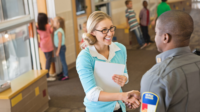 School teacher welcoming police officer with a smile and a hand shake
